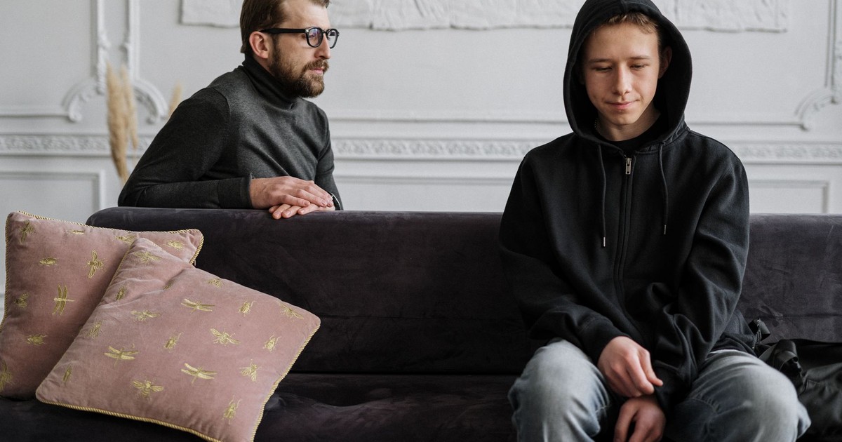 Teen in black hoodie during a therapy session in a calm indoor setting.
