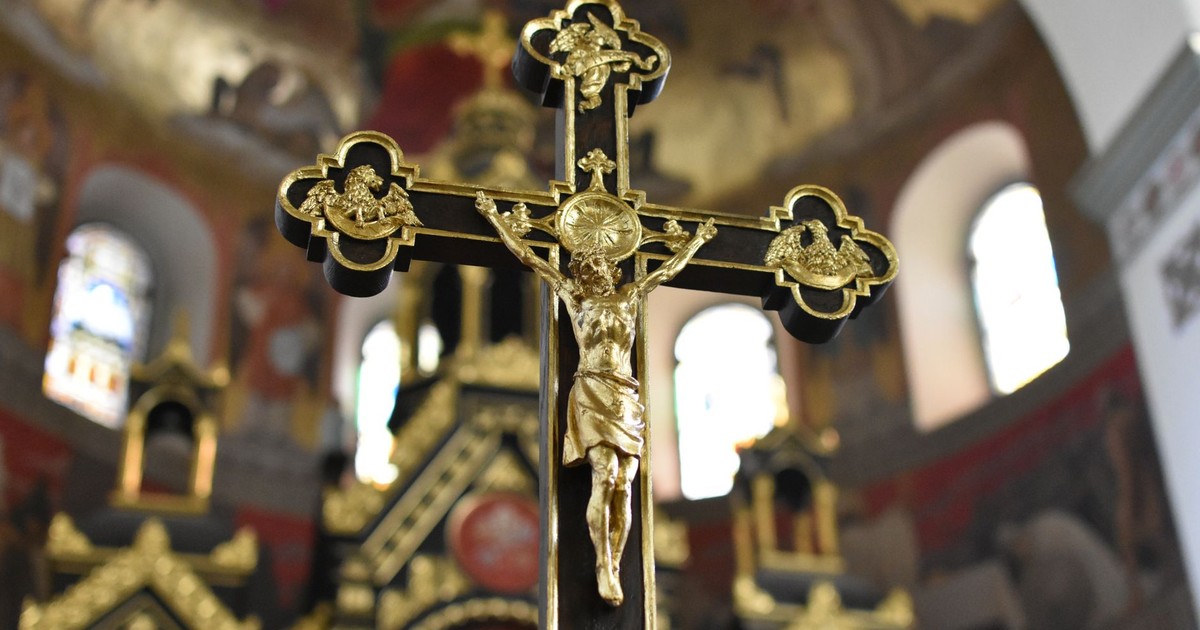 Close-up of a detailed gold crucifix in an elaborate church interior, symbolizing Christian faith and spirituality.