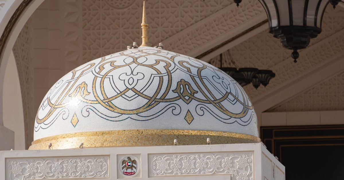 Close-up of a beautifully decorated dome inside a grand mosque, showcasing intricate Islamic patterns.