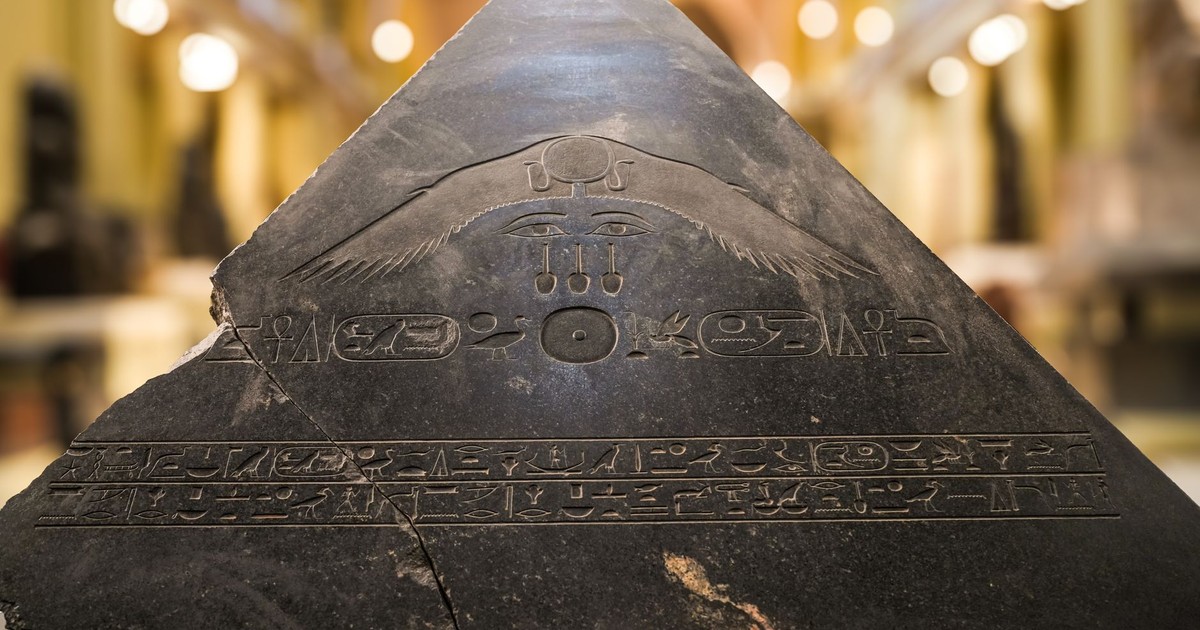 Close-up of a pyramidion with ancient Egyptian hieroglyphs featuring symbolic carvings.