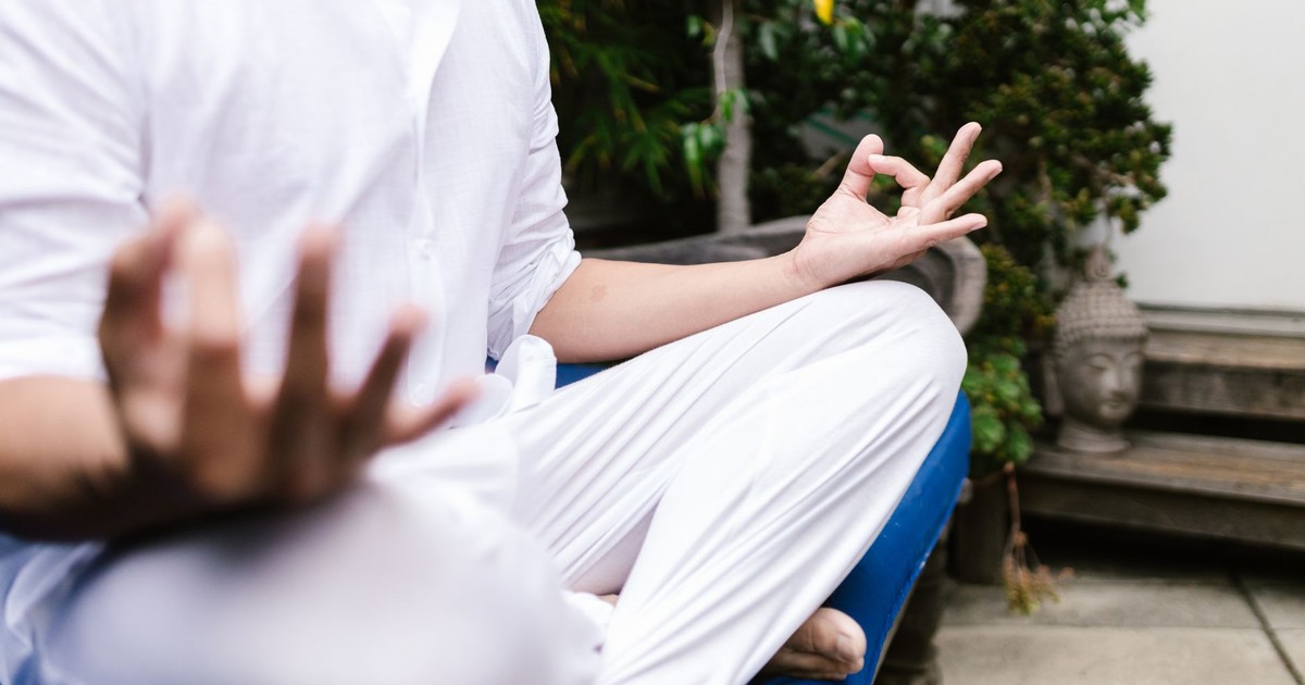 A person in white practicing yoga meditation outdoors in a serene environment.