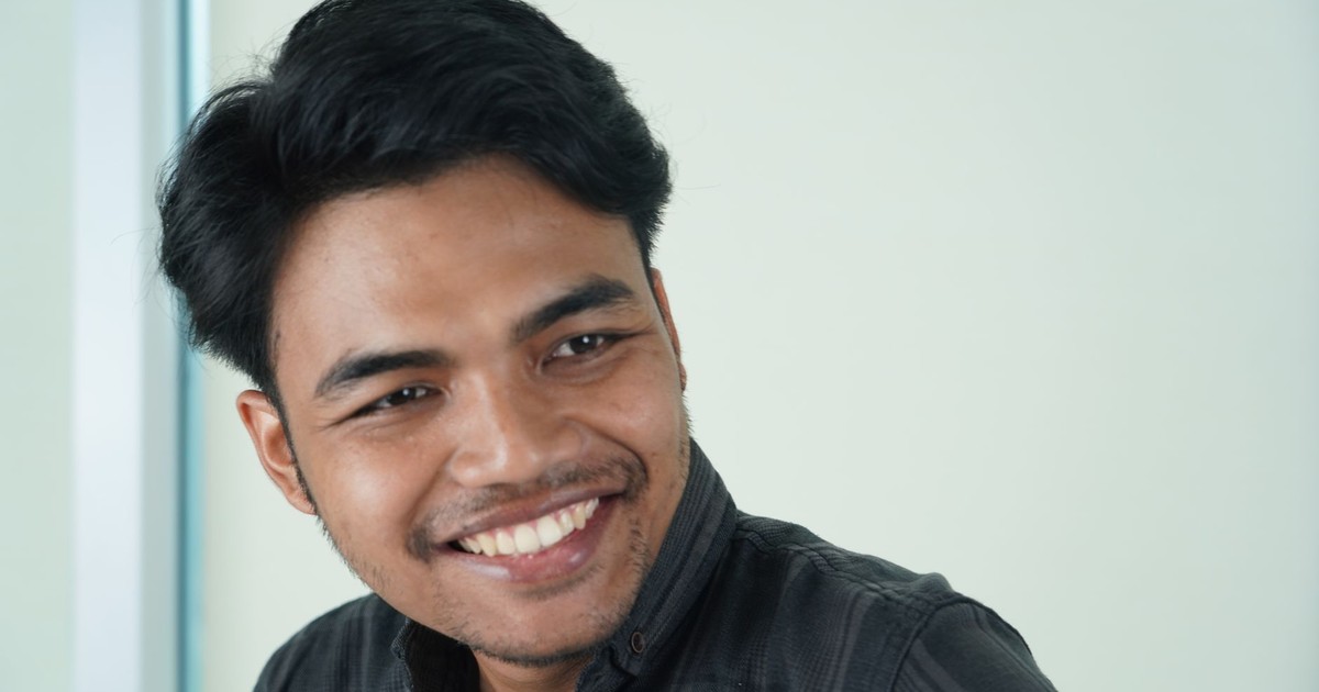 Portrait of a young man smiling, creating a positive and approachable vibe indoors.