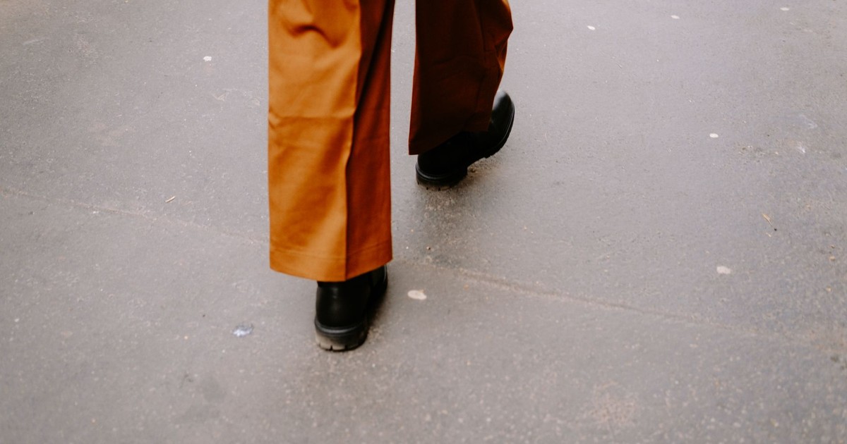 Close-up walking scene with black shoes and brown pants on a city street.