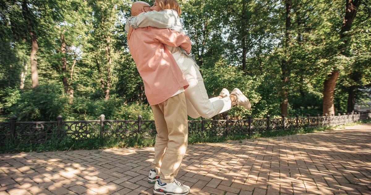 Happy senior couple embracing in a sunlit park during summer, capturing a moment of joy and love.