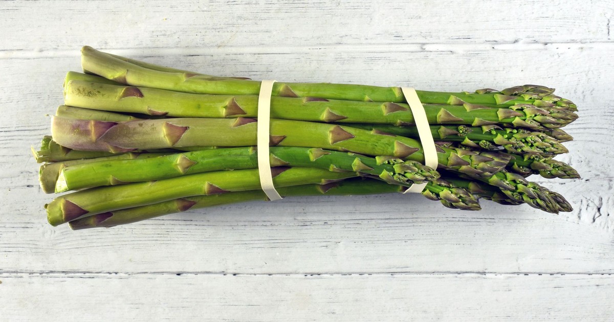 A close-up view of a fresh asparagus bundle on a rustic wooden background, highlighting its vibrant green color.