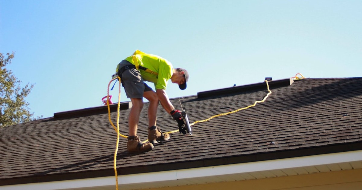 a man working on a roof with a power drill