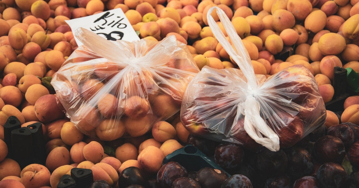 Plastic bags of apricots and plums at a vibrant Turkish market stall. Fresh produce in Alanya, Türkiye.