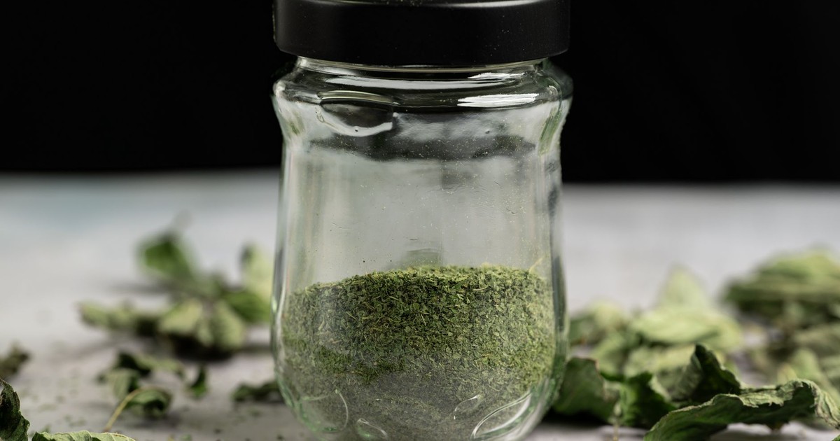 Close-up of a glass jar filled with dried, powdered mint leaves, ideal for culinary use.
