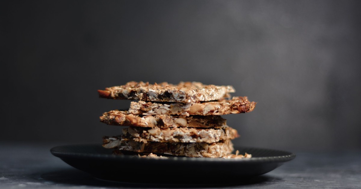 Close-up of a stack of homemade granola bars on a dark plate against a moody background.