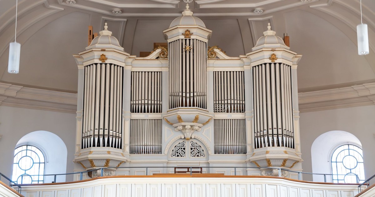 Majestic white pipe organ in a grand church interior with intricate design details and high ceilings.
