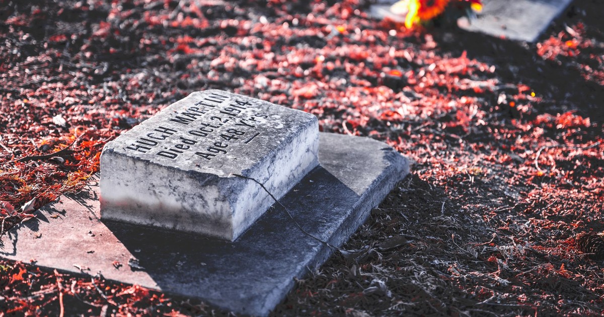 A peaceful autumn cemetery scene with a weathered tombstone and vibrant leaves.
