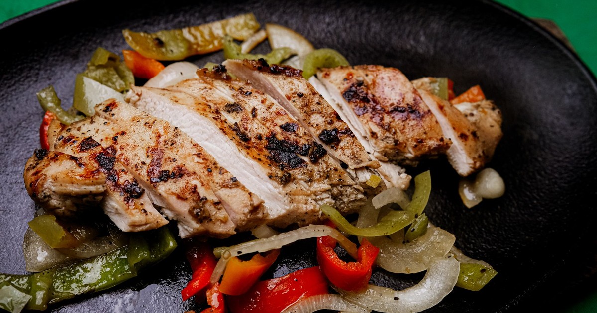 Succulent grilled chicken with vibrant peppers on a sizzling plate, perfect for a tasty meal.