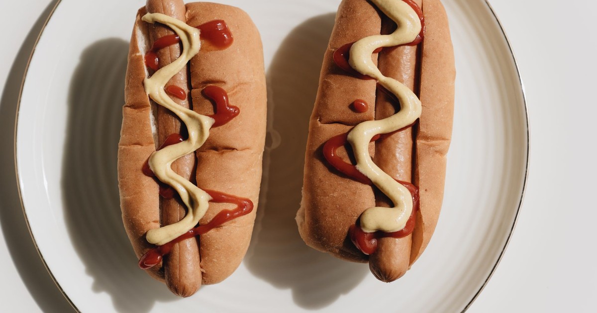 Two hot dogs on a plate topped with ketchup and mustard, ready to eat.