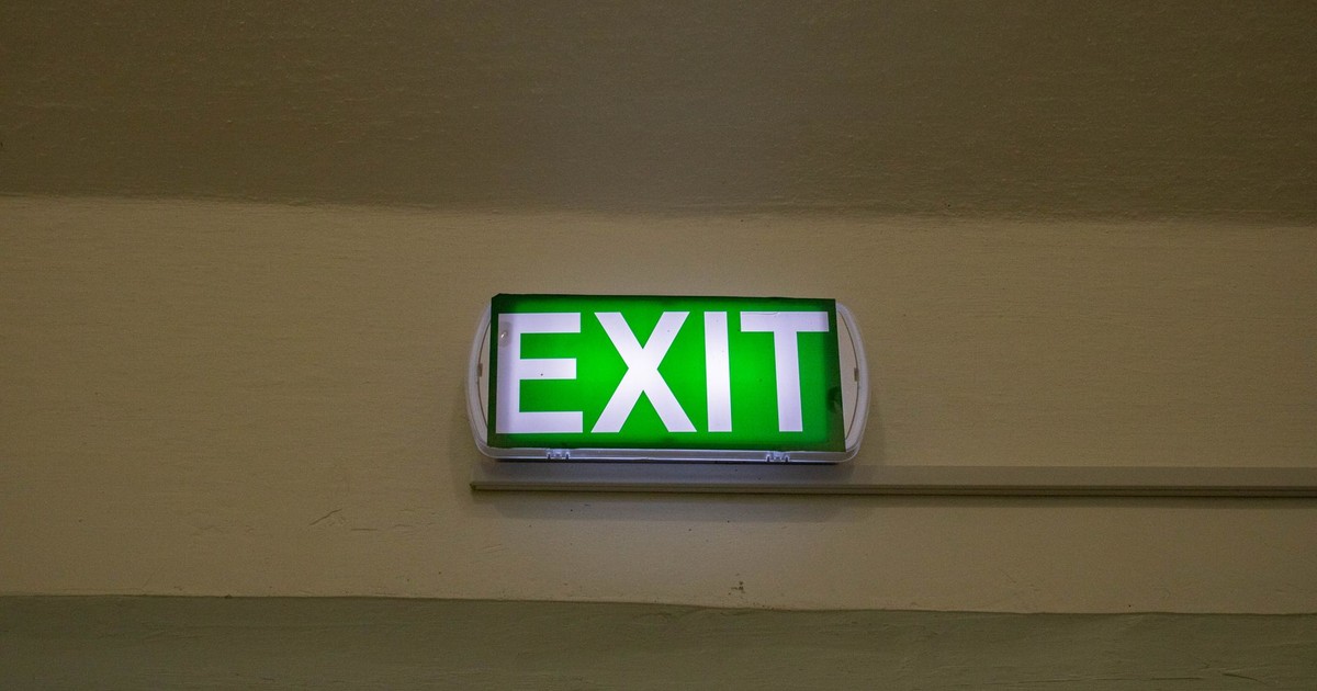 Bright green exit sign mounted on a hallway wall, offering clear direction for emergency evacuation.