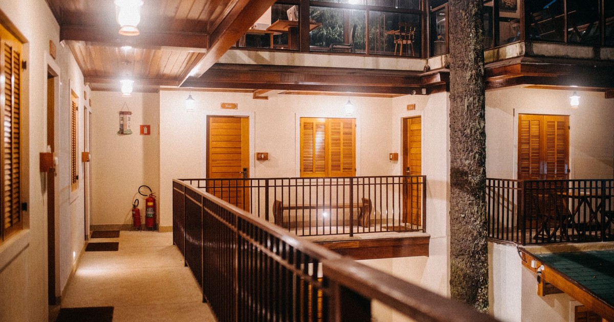 Contemporary dwelling building with hallway on fenced balcony with doors illuminated by shiny lights at night