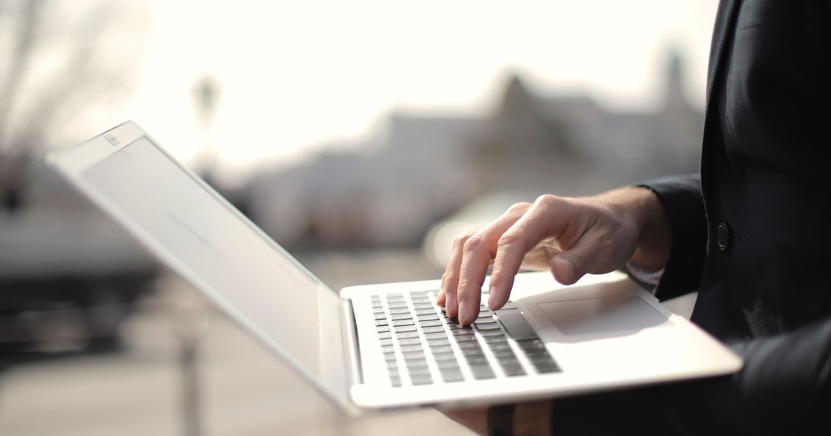 A business professional typing on a laptop in an outdoor setting, symbolizing remote work.