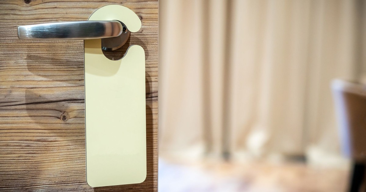 A close-up of a wooden door with a metallic handle and blank hanger in a cozy interior setting.