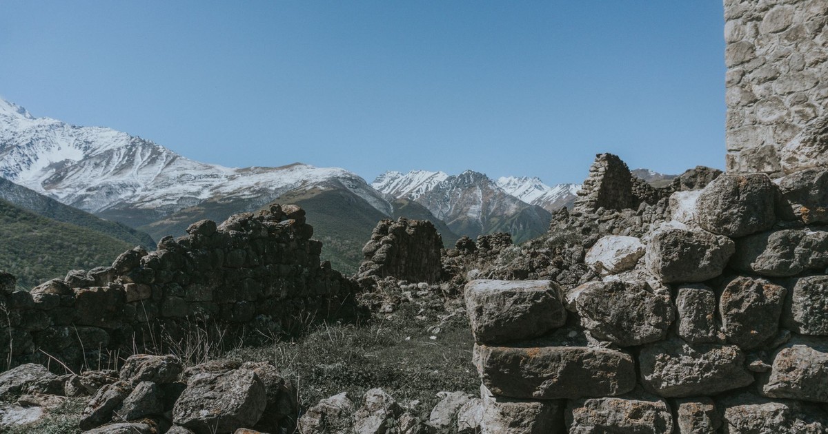 Explore the scenic mountains and ancient stone ruins of North Ossetia under a clear blue sky.