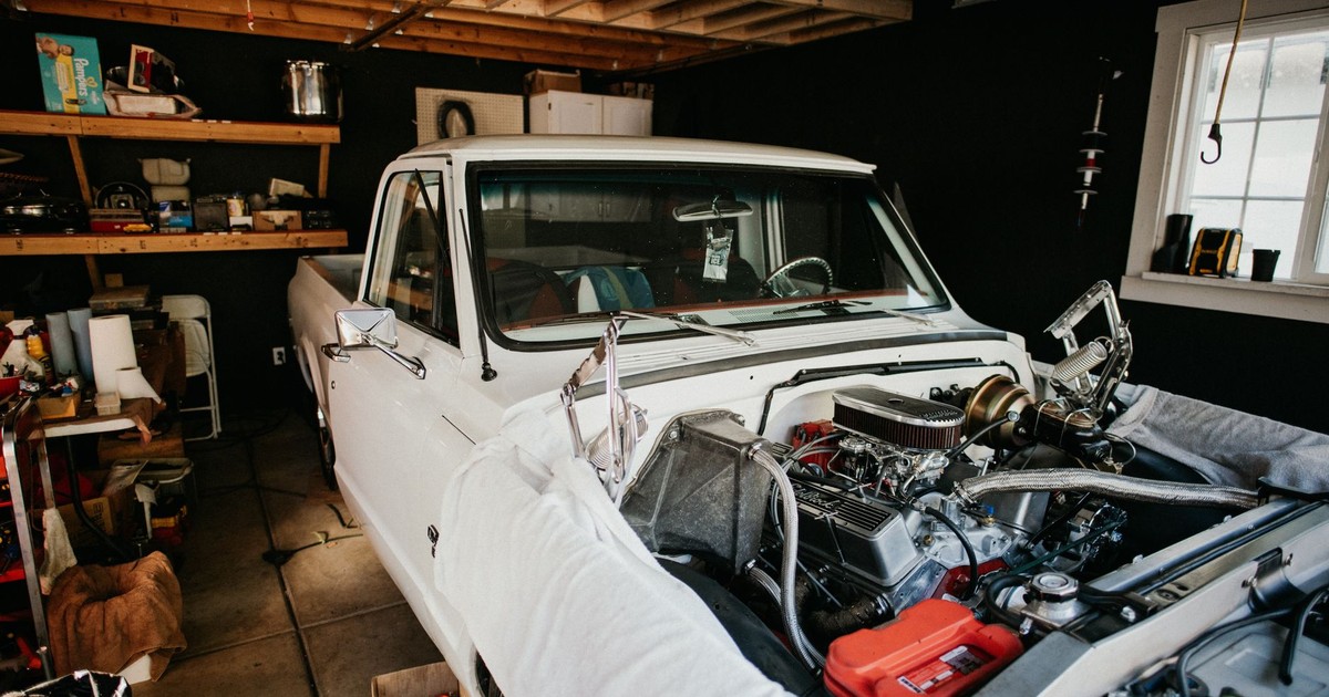 A vintage pickup truck undergoing engine repairs in a well-equipped home garage.