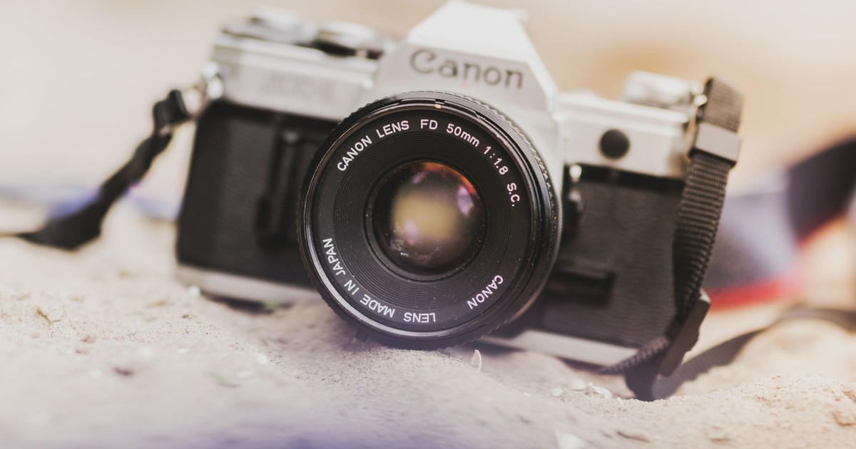 Close-up of a vintage camera lens focused on a sandy surface, ideal for photography themes.