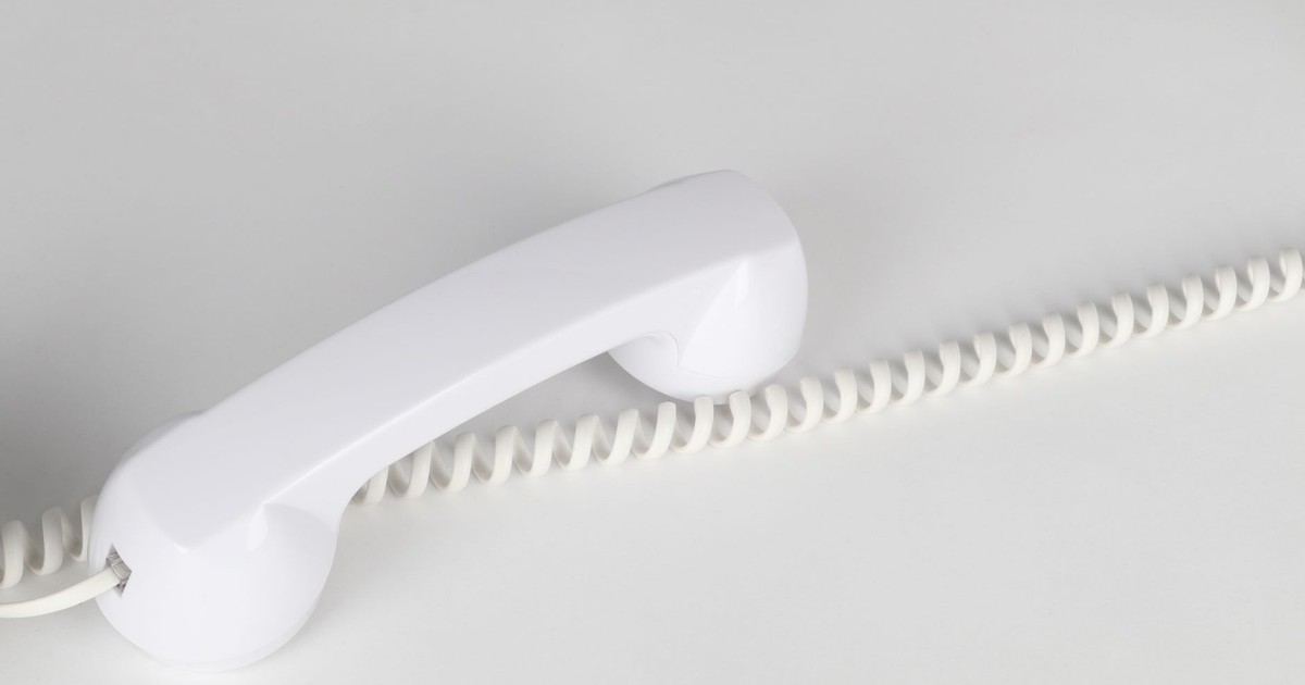 Simple and elegant close-up of a white corded telephone handset on a white background, emphasizing minimalism.