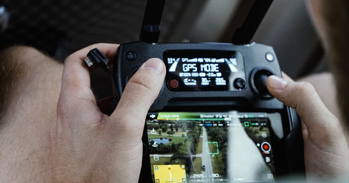 Close-up of hands operating a modern drone controller with GPS mode displayed.