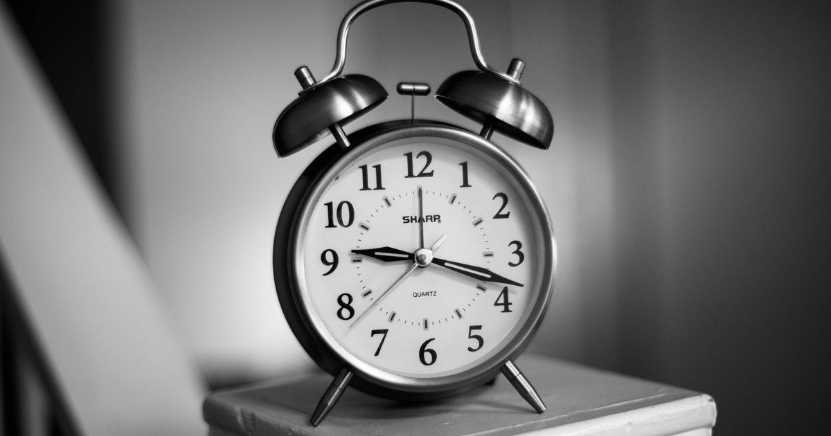 Close-up of a monochrome analogue alarm clock, showcasing time precision.