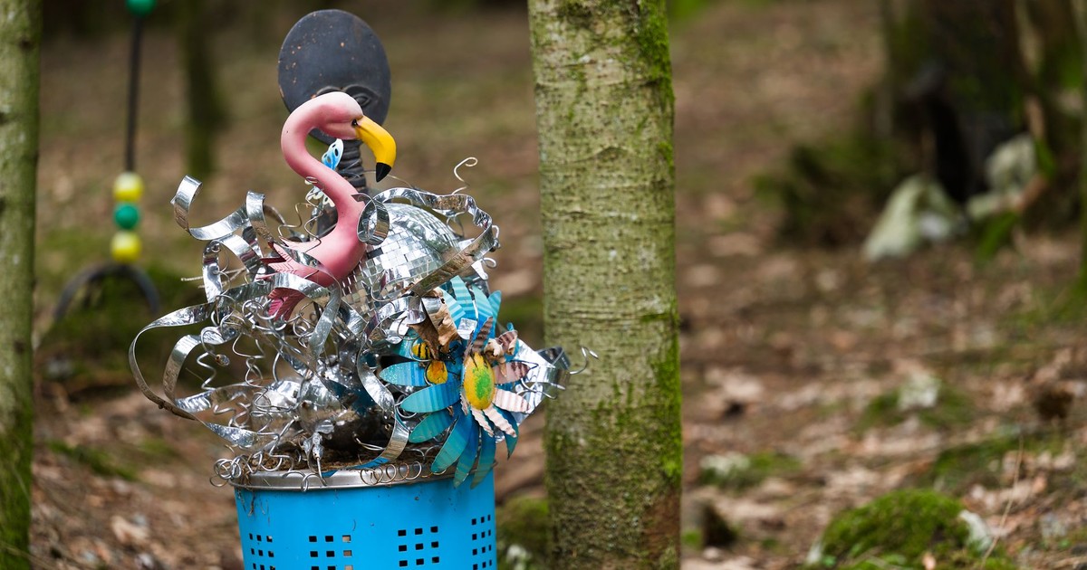 Vibrant sculpture of flamingo and flowers in a serene forest.