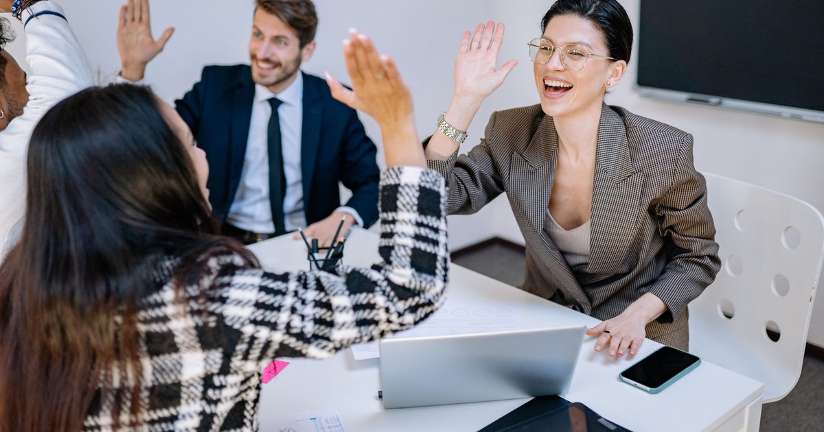 A diverse group of colleagues celebrating success with high fives in a modern office.
