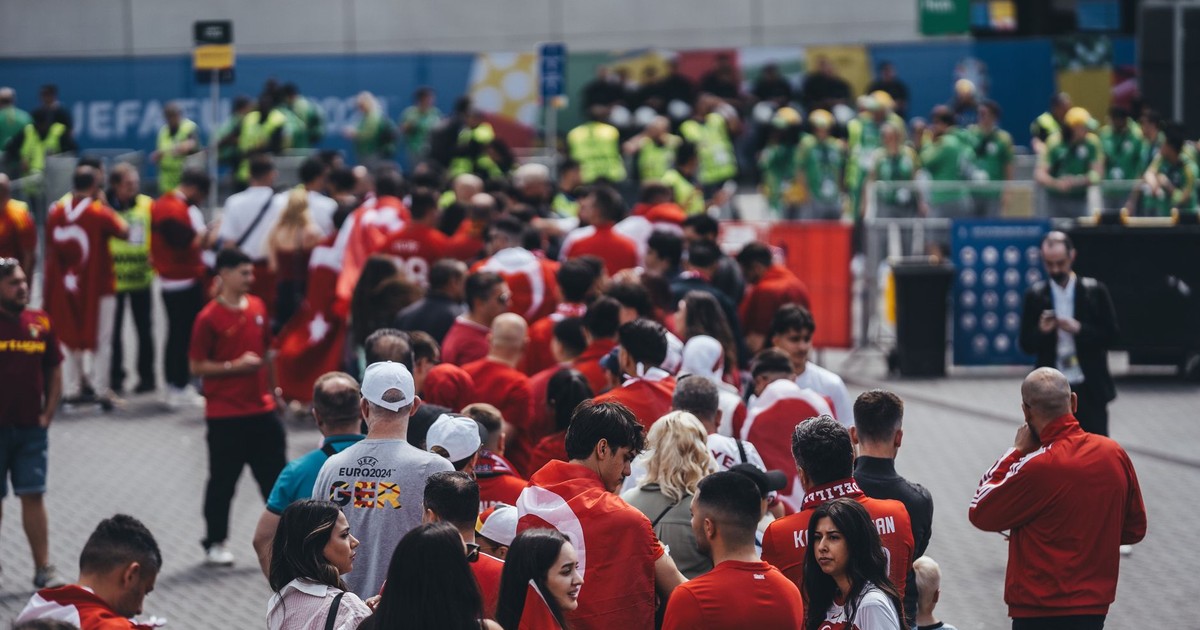 A large group of fans in red jerseys queuing outdoors for a sports event entrance.