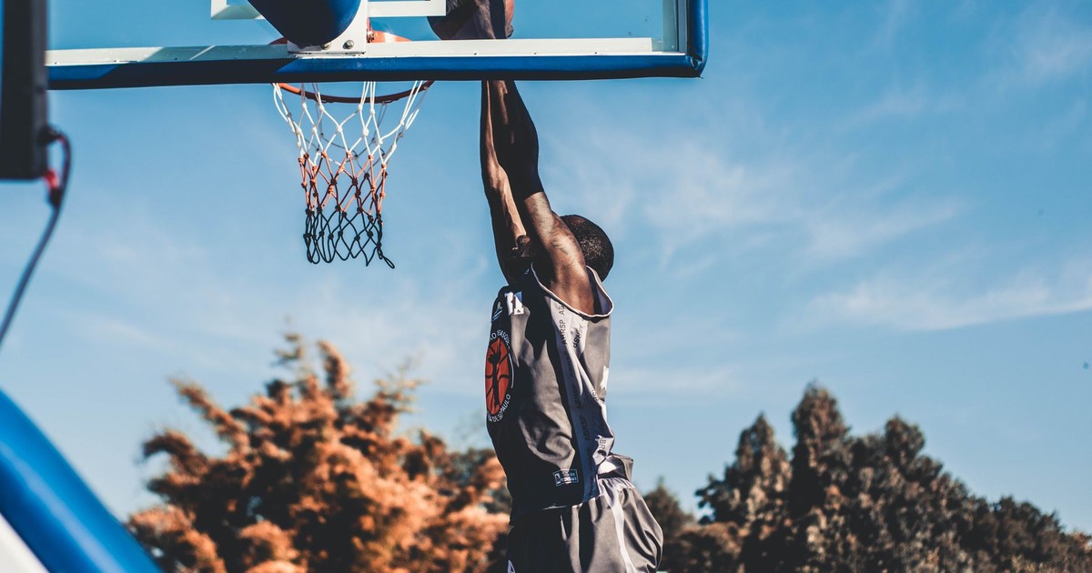 High-energy basketball dunk captured outdoors during daytime play.