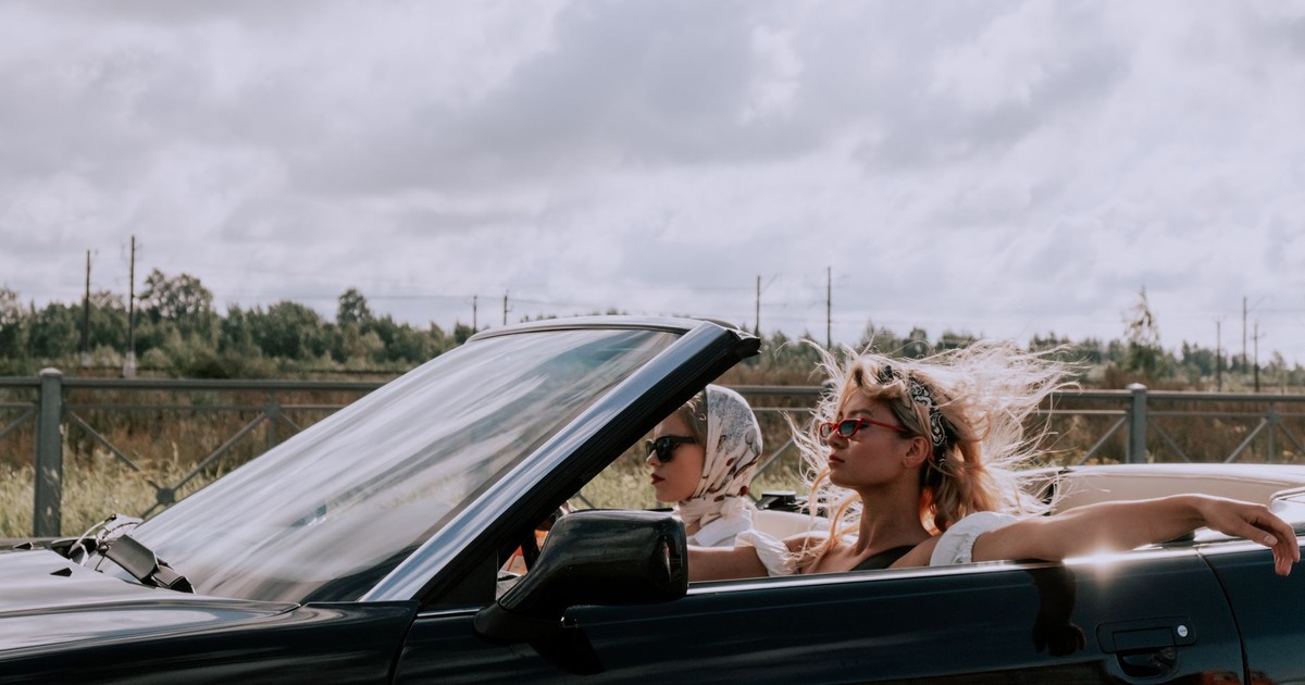 Two fashionable women driving a convertible with sunglasses, capturing the essence of freedom and style.