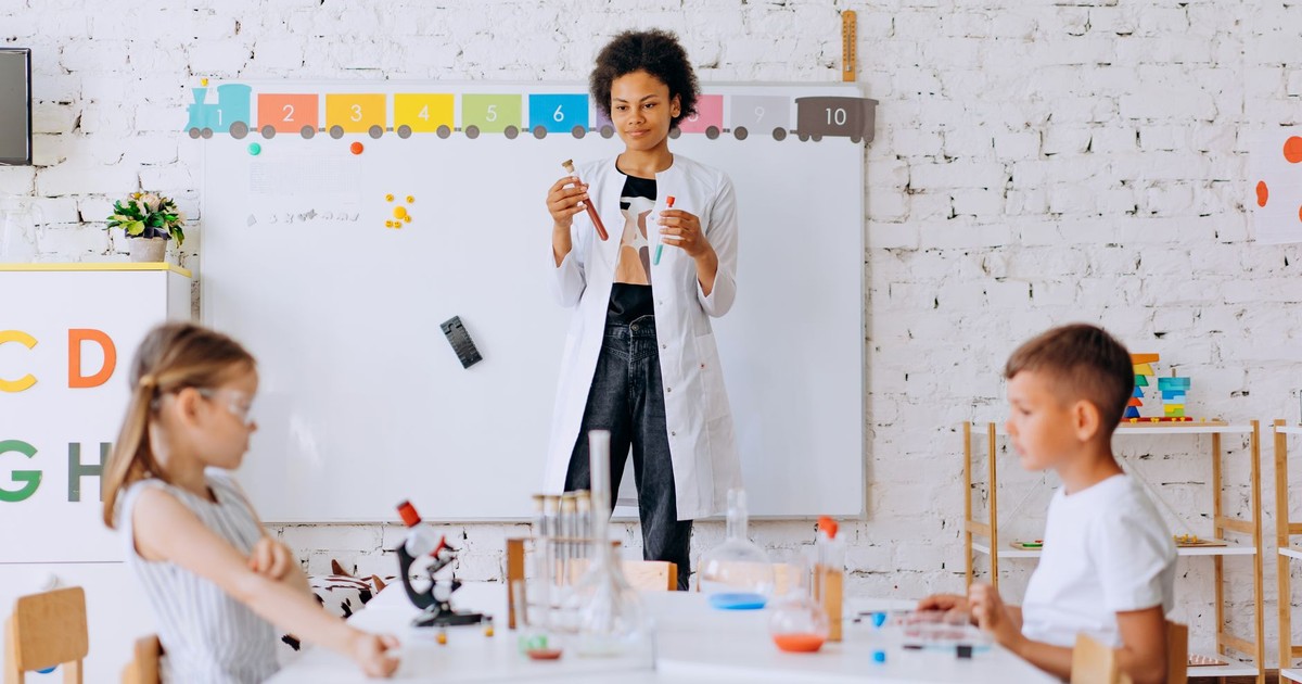Children conduct a science experiment under teacher's guidance in a classroom setting.