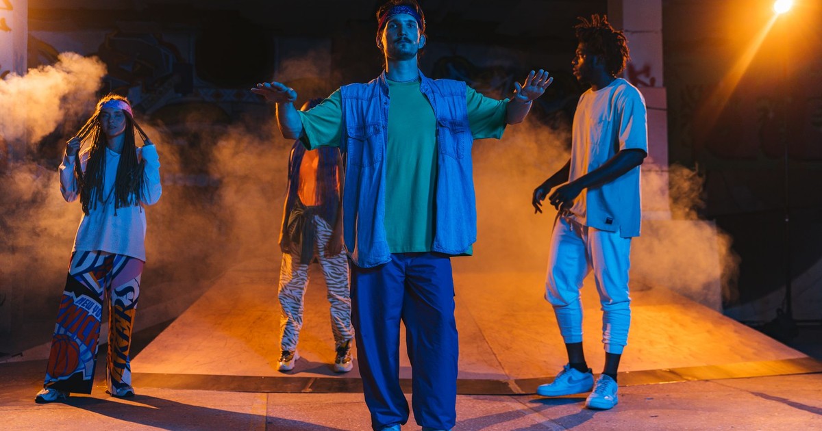 Energetic group of young dancers performing indoors with dramatic lighting and smoke effects.