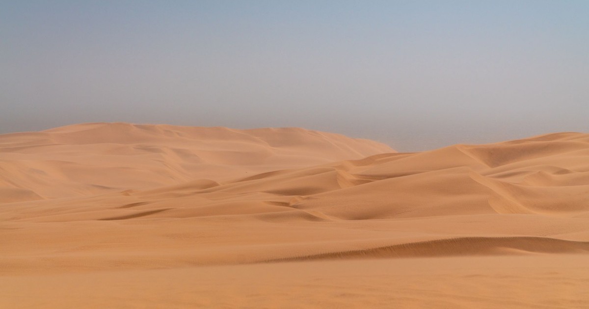 Serene sand dunes under a clear sky in the Namib Desert, showcasing natural beauty.