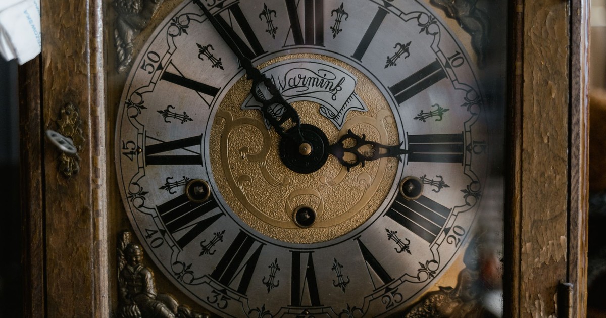 A detailed view of a vintage clock with Roman numerals and ornate design.