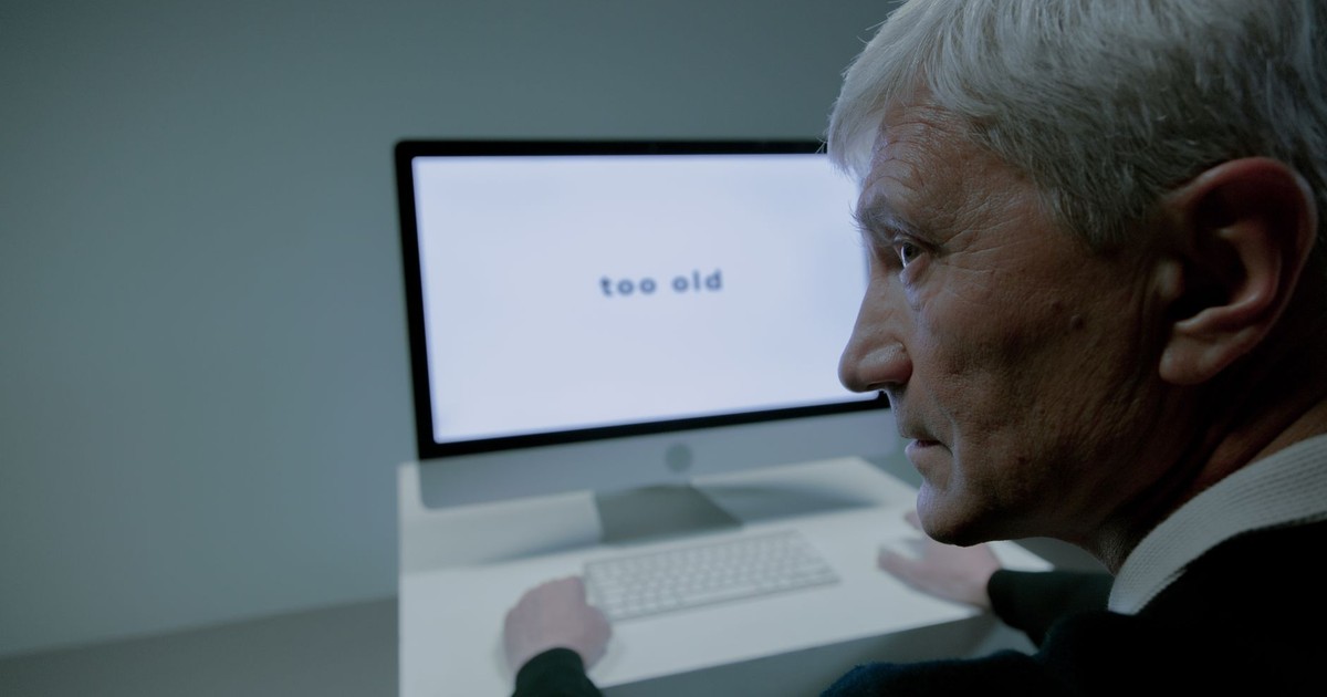 Senior man confronted with ageism on computer screen in job search.