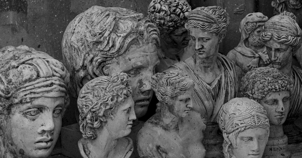 A group of vintage stone head bust sculptures in grayscale, depicting ancient figures.