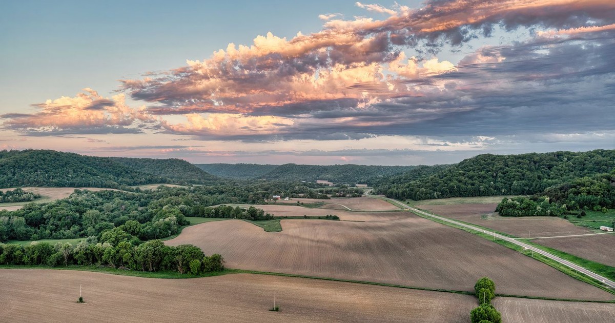 Stunning sunset aerial view of Weaver, MN's rural landscape showcasing fields and forests.