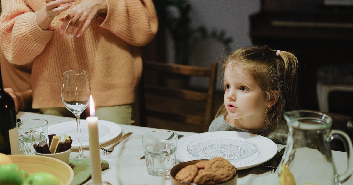 A warm, intimate family dinner setting with a child at the table, enjoying a cozy atmosphere.