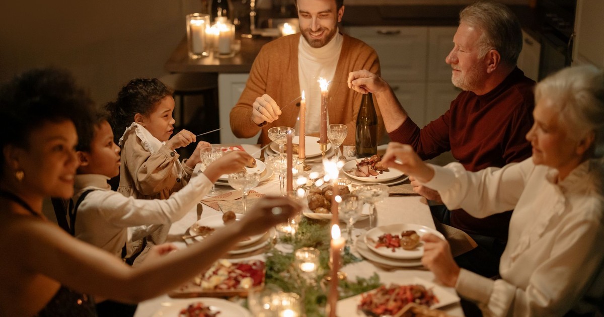 Family enjoying a festive dinner together indoors with warm candlelight.