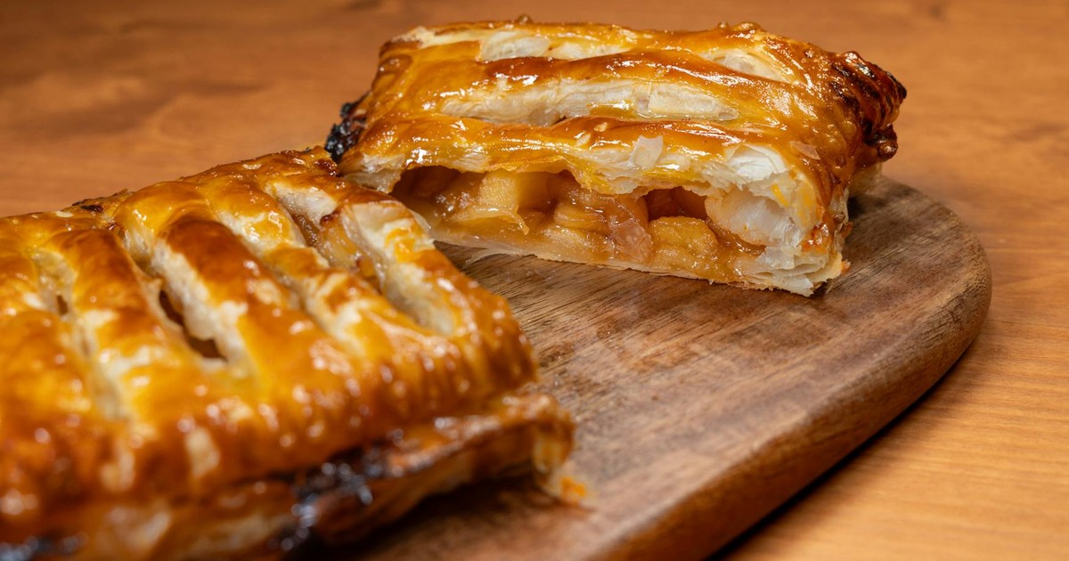 Delicious freshly baked apple strudel with golden flaky pastry on a wooden board.