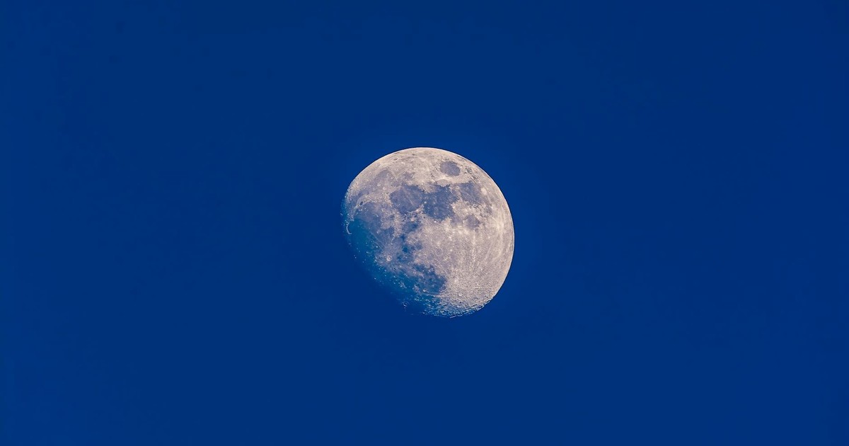 A clear view of the waxing gibbous moon set against a vibrant blue sky, showcasing lunar details.