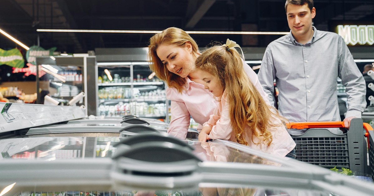 A happy family shopping in the supermarket's freezer section, emphasizing togetherness and love.
