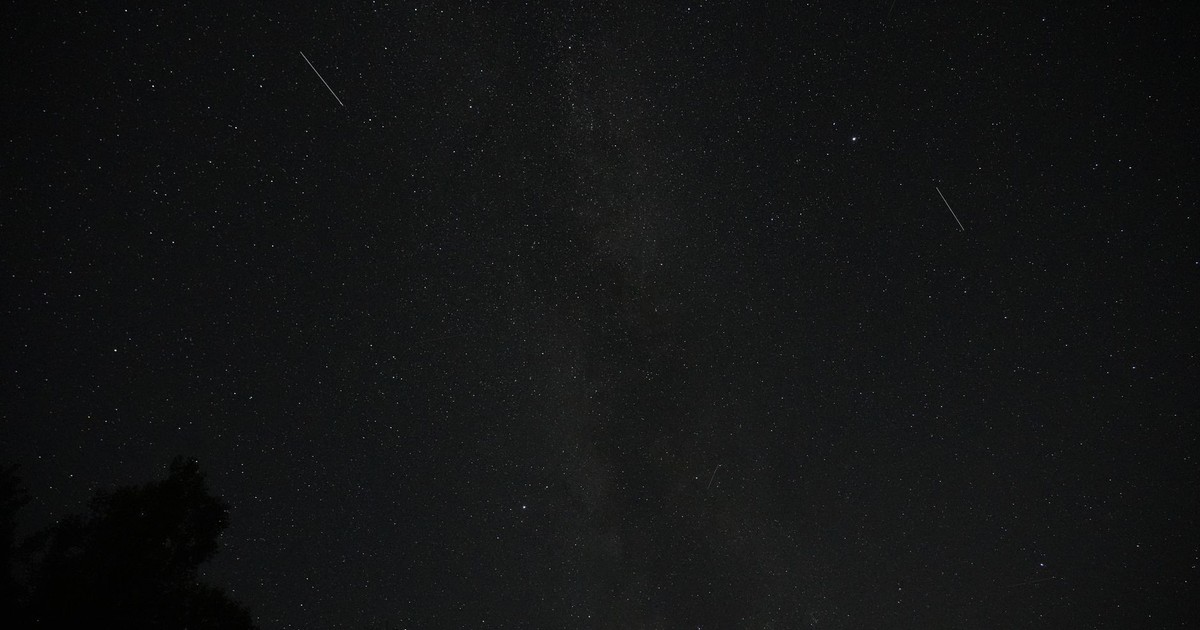 A dark night sky filled with stars and visible shooting stars.