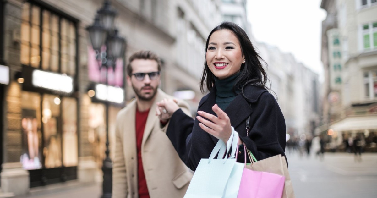 Joyful couple shopping and enjoying a sunny day in the city with shopping bags. Perfect for lifestyle and urban tourism themes.