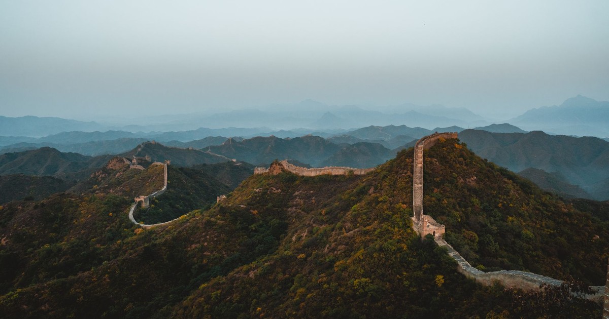 Scenic aerial view of the Great Wall of China stretching across rugged hills at dusk.
