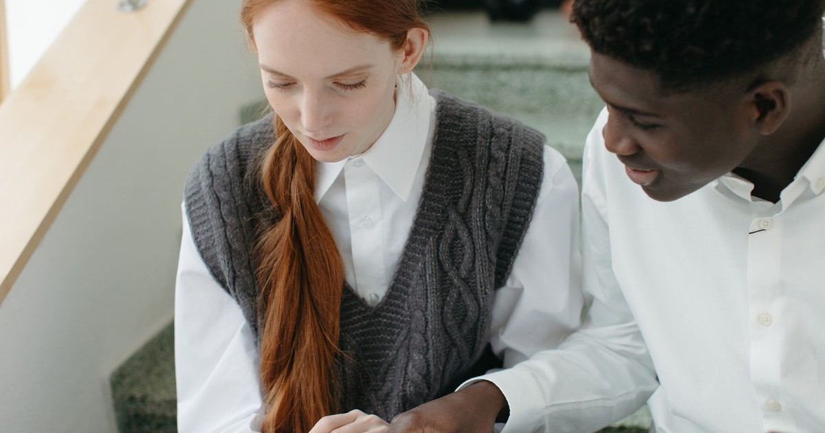 Young couple studying together indoors, focusing on a document. Educational setting.