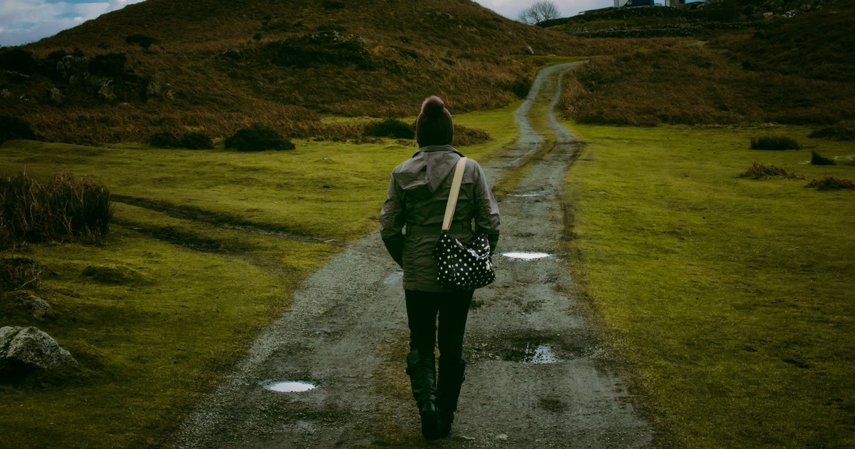 Person walking on a scenic countryside trail, embracing solitude and nature.