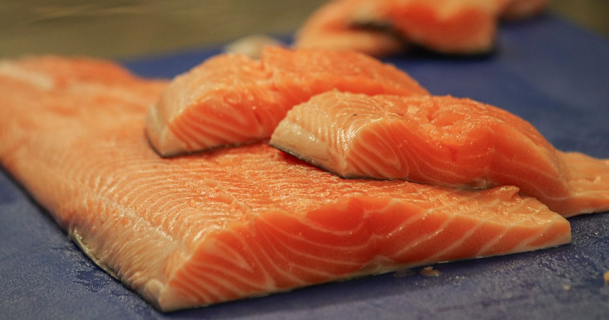 Close-up of fresh salmon fillets on a blue cutting board, ready for cooking.